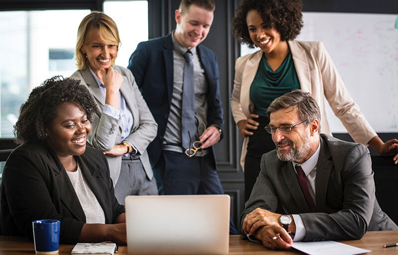 business people gathering around computer in office